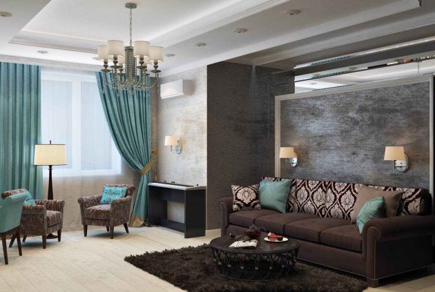 Contemporary living room with a dark brown sofa and patterned cushions, teal accent chairs and curtains, a chandelier overhead, and wall-mounted lamps framing a textured gray feature wall.