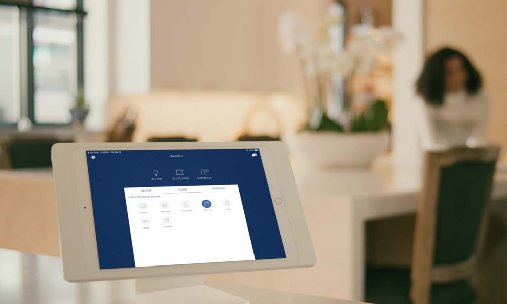 Tablet on a stand showing a smart home control interface in a softly lit room.
